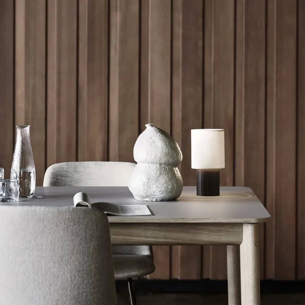 Warm light from the portable Solene lamp on a table against a wood-panelled wall