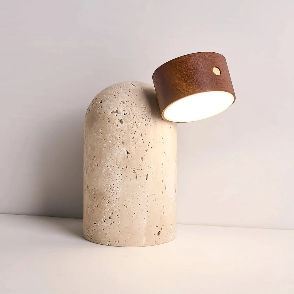 The adjustable walnut head of the Sten lamp turned to the right, lit above the domed travertine base