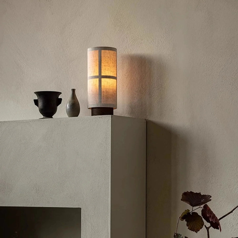 Warm light from the portable Washi lamp on a plaster ledge, casting a soft glow up the wall