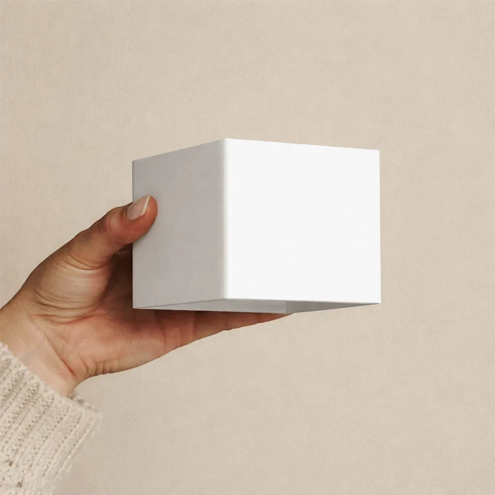 A hand holding the Cubo wall light, showing it is roughly the size of a fist