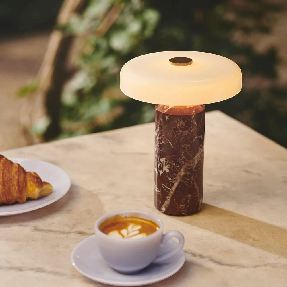Halo burgundy marble table lamp lit on a cafe table with coffee and a croissant, HALO-BURG-01