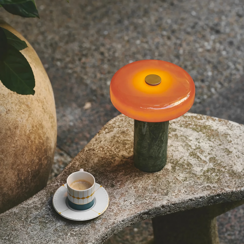 Halo green marble table lamp lit on a stone garden bench beside an espresso cup, HALO-GREEN-01
