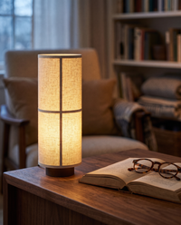 Washi table lamp lit on a desk in a cosy reading nook at dusk